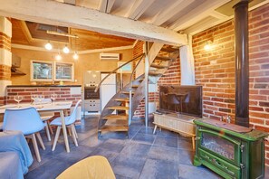 A modern kitchen with a dining area, a staircase, and a green wood-burning stove. - Flore - au cœur du bassin d'Arcachon (Arcachon)
