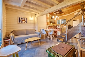 Un interior acogedor con un sofá, una mesa de comedor y sillas. Una escalera conduce a un nivel superior.