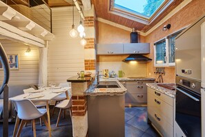 A compact kitchen with a central island, a dining area with chairs, and a view through a skylight. - Flore - au cœur du bassin d'Arcachon (Arcachon)