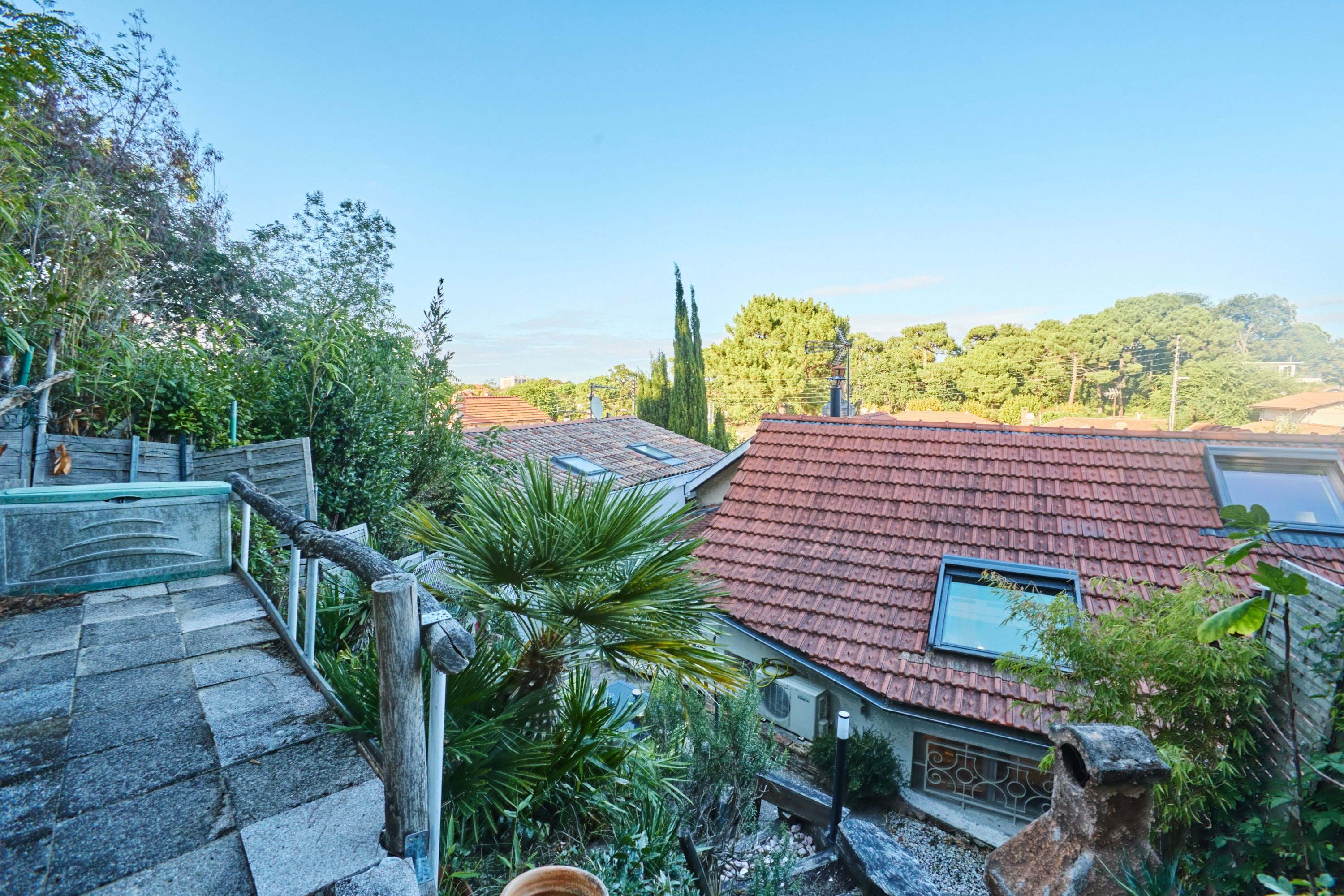 A residential area with a staircase leading to a house with a red-tiled roof.