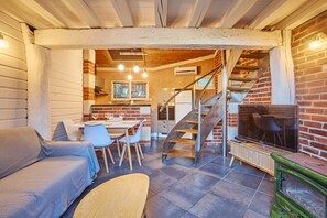 A cozy living area with a sofa, a dining table with chairs, a staircase, and a television. - Flore - au cœur du bassin d'Arcachon (Arcachon)
