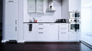 Una cocina moderna con armarios blancos, una campana extractora de acero inoxidable y electrodomésticos integrados, incluyendo un microondas y un horno.