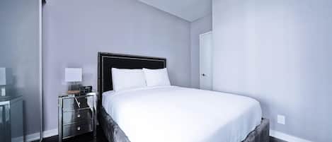 Une chambre moderne avec un grand lit, une table de chevet avec une lampe et un miroir.