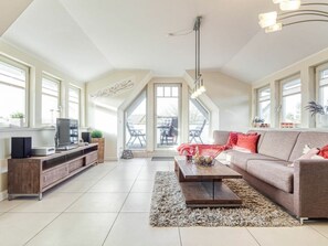 A spacious living room with a high ceiling, a television, a sofa, and a coffee table. - Kavelweg 9 Apt. 5 (Zingst)