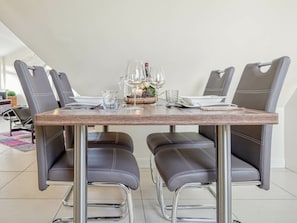 A dining area with a rectangular table, six chairs, and a center setting with a glass pitcher, wine glasses, and a small vase. - Kavelweg 9 Apt. 5 (Zingst)