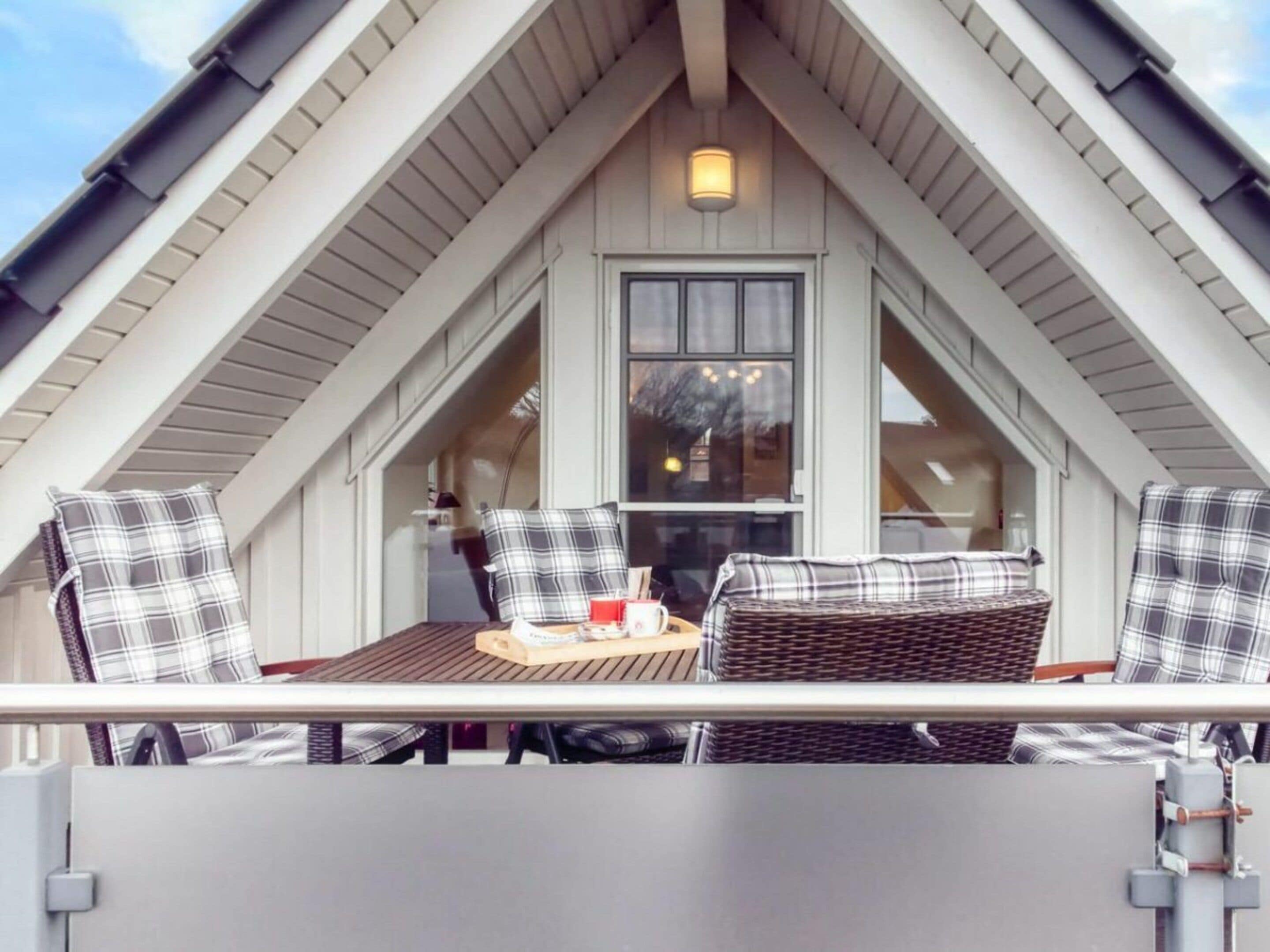 A balcony with a table and chairs, a window, and a light fixture.