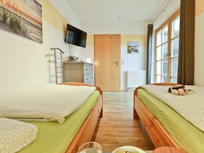 Ein Hotelzimmer mit zwei Betten, einem Fernseher, einem Heizkörper und einem Fenster.