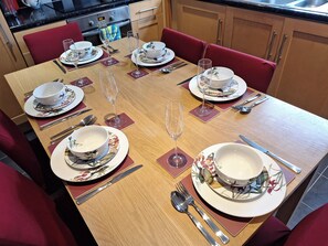 A dining table set with plates, bowls, wine glasses, and cutlery. - Fryers Cottage (Scarborough)