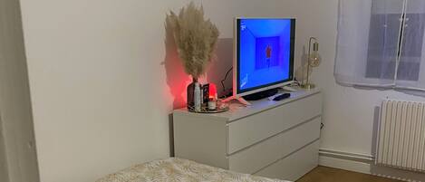 A bedroom with a bed, a TV, a dresser, and a window.