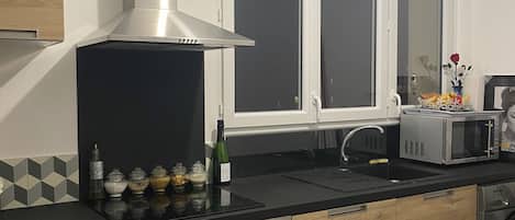 A modern kitchen with a built-in oven, a microwave, and a stainless steel range hood.