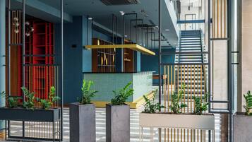 A modern interior with a staircase, a reception desk, and potted plants.