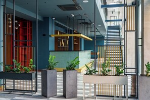 Een modern interieur met een trap, een receptiebalie en potplanten.