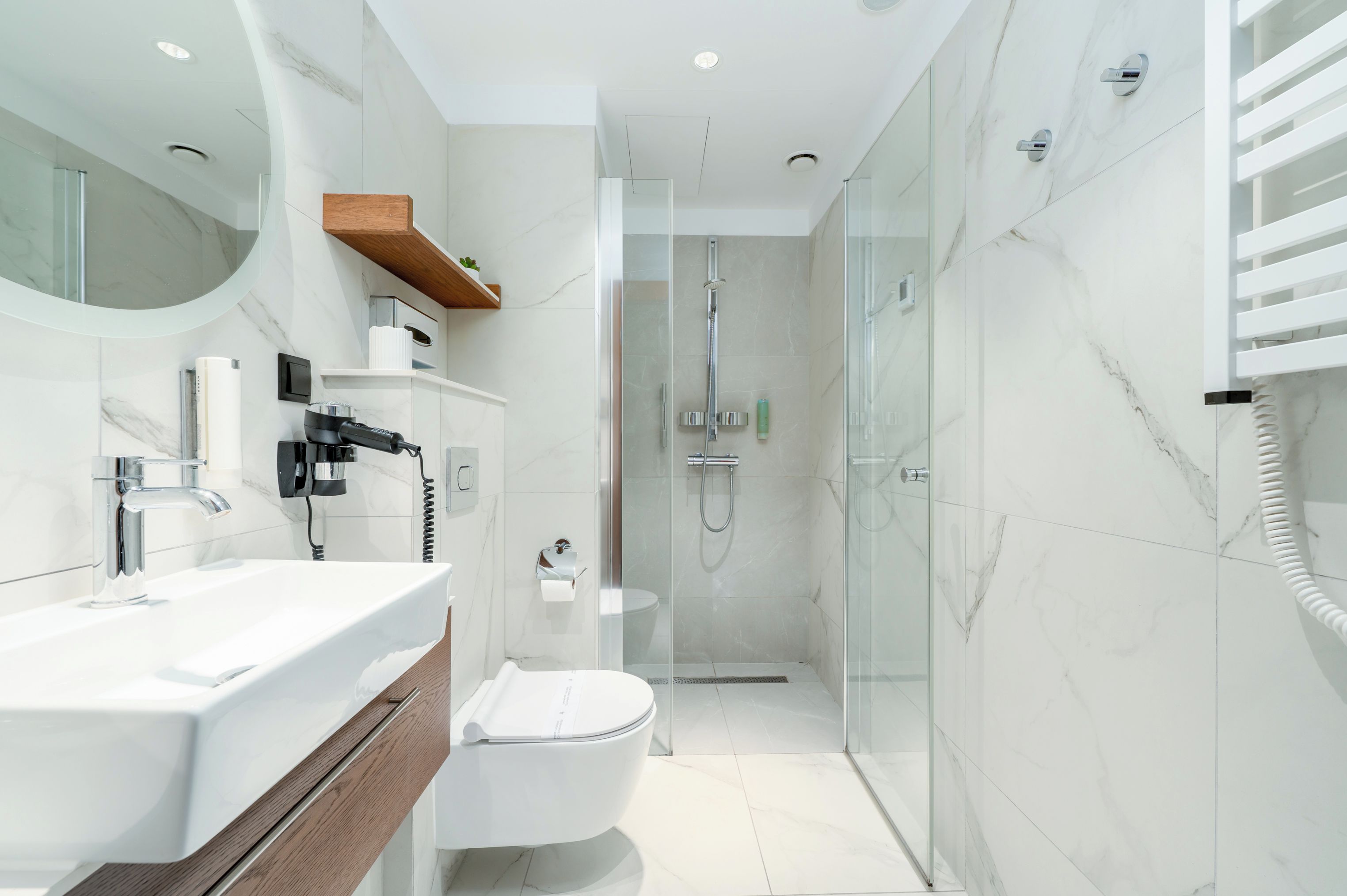 A modern bathroom with a glass-enclosed shower, a white toilet, and a vanity with a mirror and sink.
