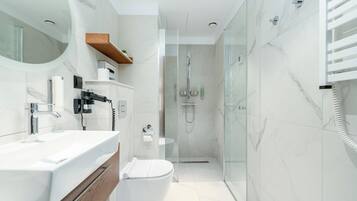 A modern bathroom with a glass-enclosed shower, a white toilet, and a vanity with a mirror and sink.