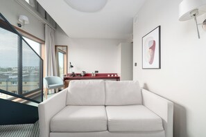 A modern living room with a white sofa, a red console table with a coffee maker, and a large window with a view. - PERON 12 GWARNA (Wrocław)