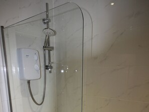 A glass-enclosed shower with a handheld showerhead and a control panel. - Cornerhouse Apartment 2 (Llandudno)