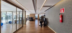A gym with exercise equipment, a fire extinguisher, and a glass wall with a view. - COOND0126 - Beach Class Salvador (Salvador)