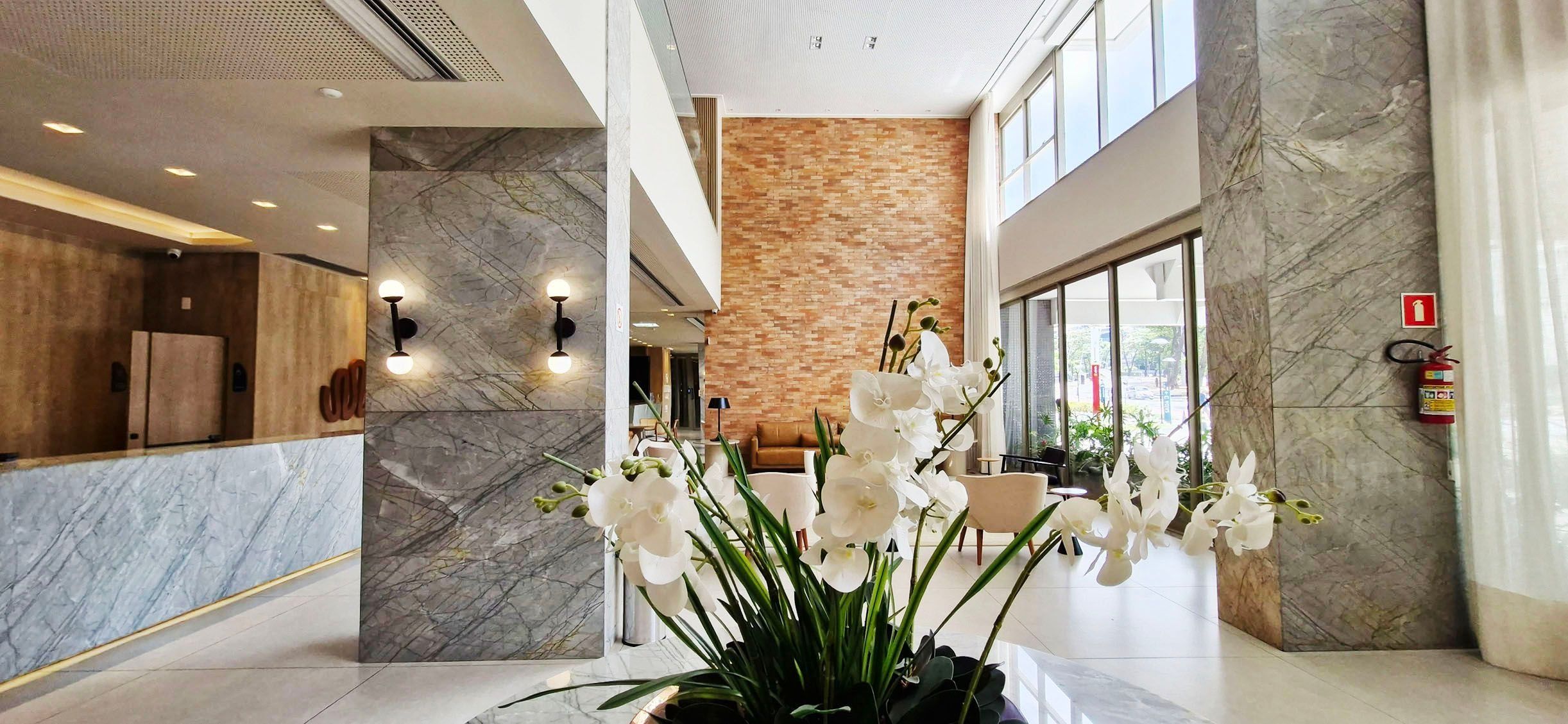 A hotel lobby with marble flooring, a reception desk, a brick accent wall, and a large window.