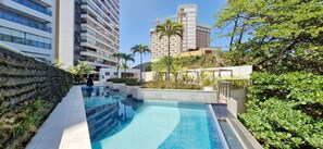 A swimming pool with a modern design, surrounded by greenery and adjacent to high-rise buildings. - COOND0126 - Beach Class Salvador (Salvador)