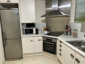 Eine kompakte Küche mit Kühlschrank, Mikrowelle, Herd, Backofen und Spüle.