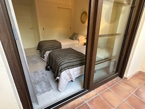 Ein Zimmer mit zwei Betten, einer Tür und einer Glastür.