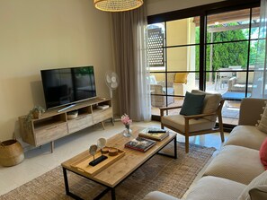 Una sala de estar moderna con televisor de pantalla plana, mesa de centro de madera y asientos cómodos.