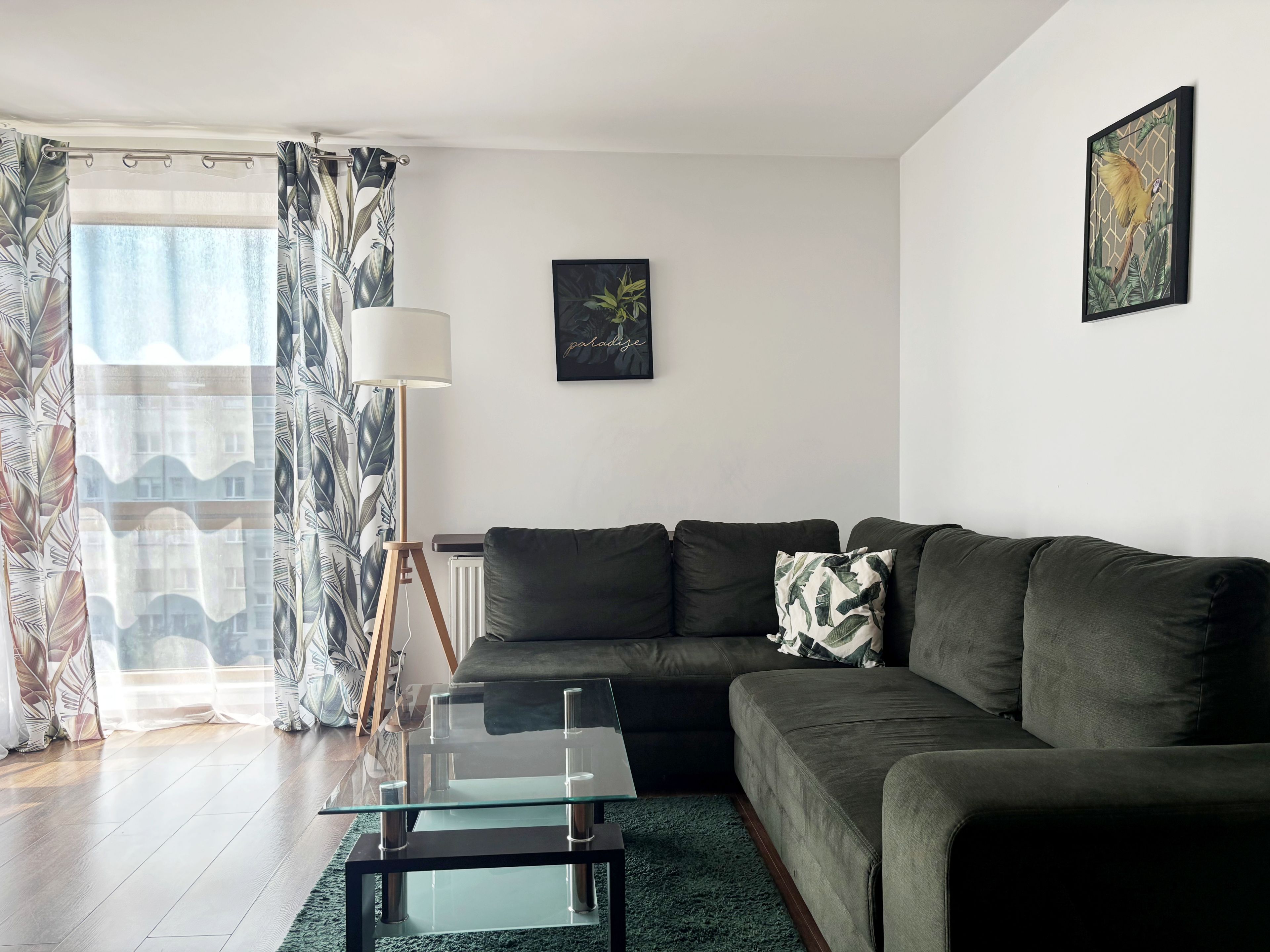 Uma sala de estar moderna com uma mesa de centro de vidro, um sofá escuro e um abajur.
