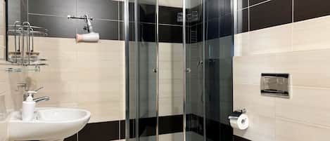 Un baño moderno con ducha envuelta en vidrio, un lavabo blanco y un inodoro.