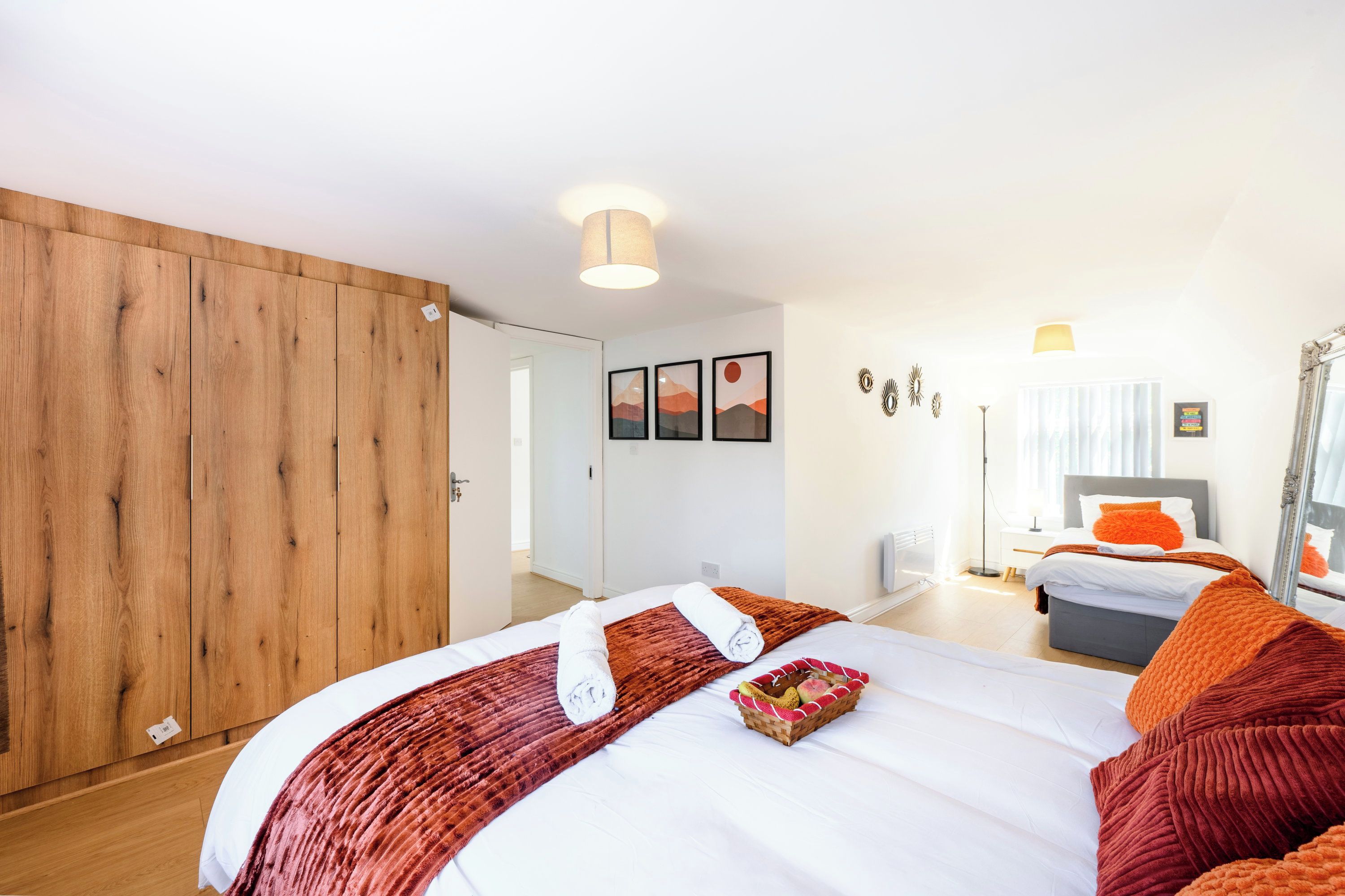 Quarto de hotel com uma cama grande, um guarda-roupa, uma escrivaninha e um espelho.