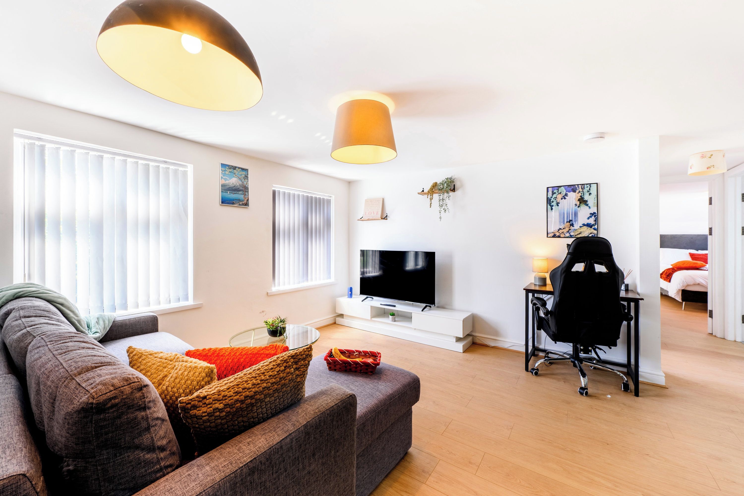 A modern living room with a sofa, TV, and a desk with a chair.