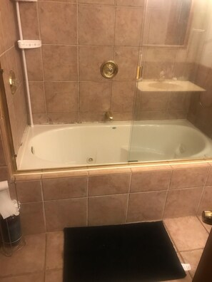 Ein Badezimmer mit einer Badewanne, einer Duschkabine und einer kleinen Ablagefläche.
