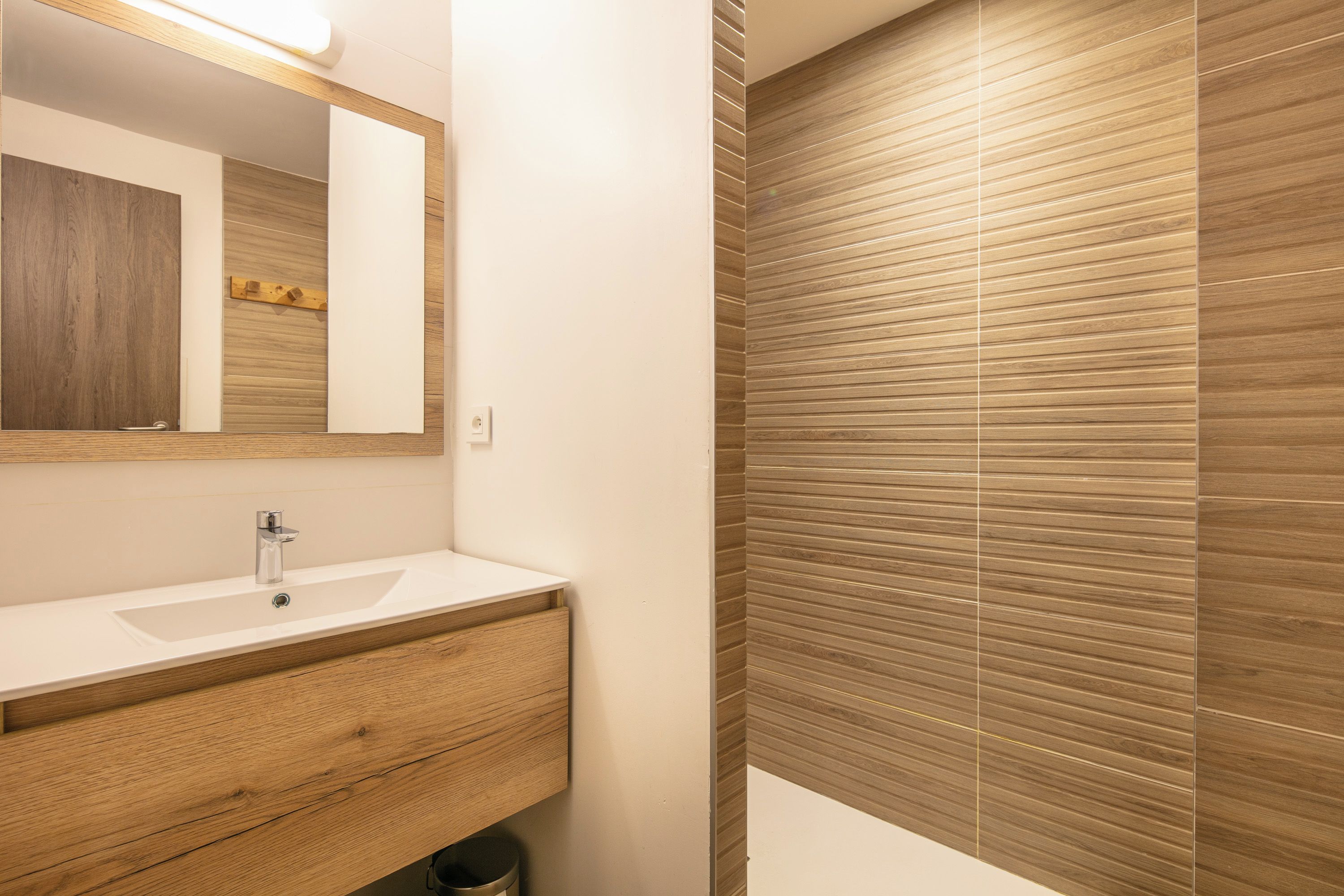 A bathroom with a wooden vanity, a sink, and a mirror.