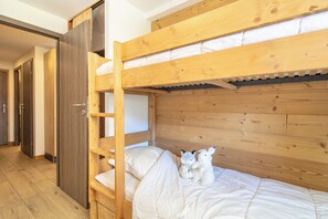 Een stapelbed met een houten hoofdbord en een onderste bed met matras en kussens.