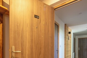 Eine Holztür mit Nummernschild, das Zimmer 2.2 zeigt, einem Türgriff und einem Schlüsselloch.