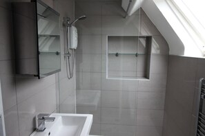 A modern bathroom with a shower, a sink, and a glass-enclosed medicine cabinet. - Cornerhouse Apartment 4 (Llandudno)