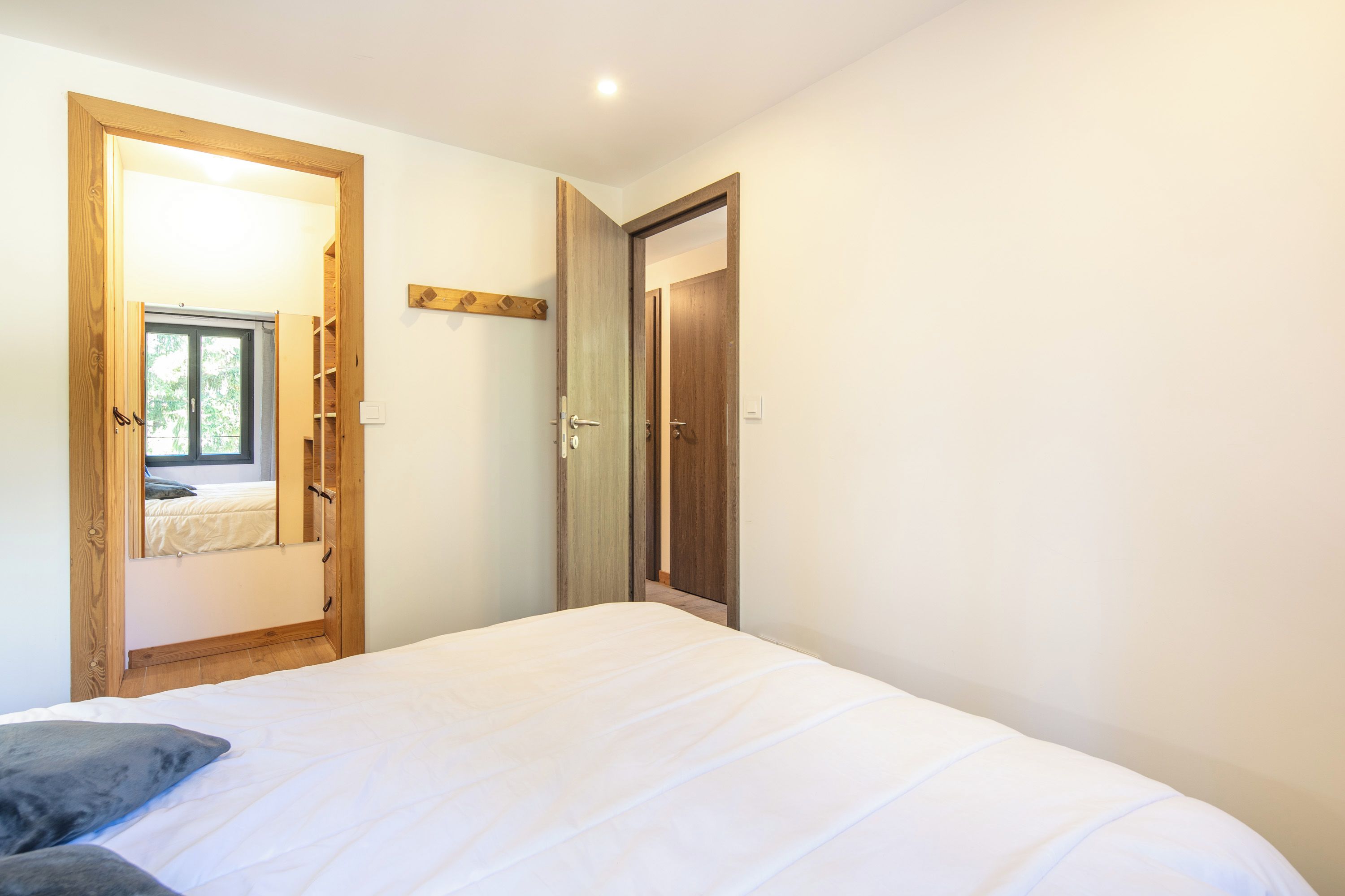 Ein Schlafzimmer mit einem Bett, einem Holzschrank und einer Tür zu einem anderen Raum.