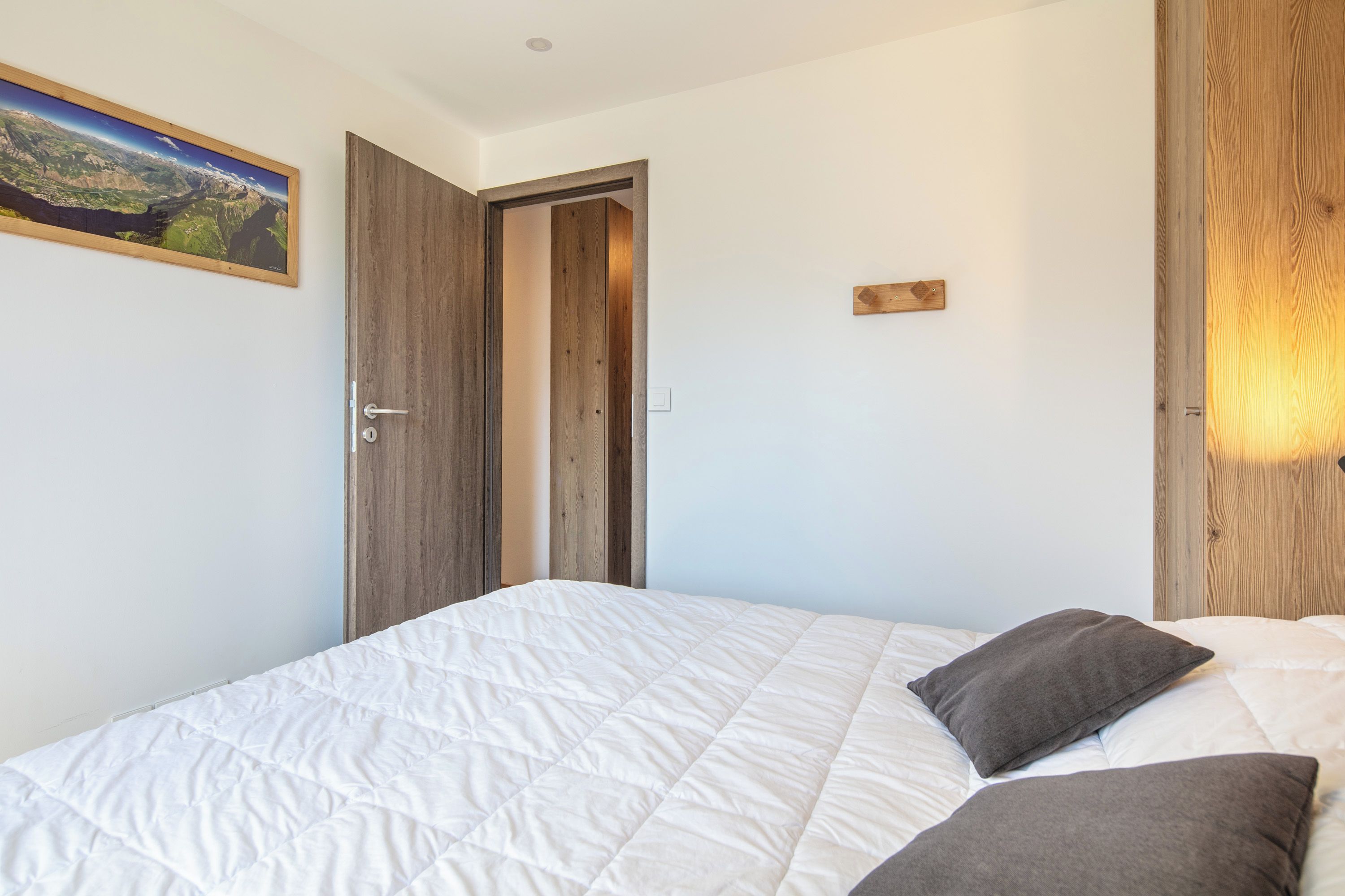 Een slaapkamer met een bed, een deur en een wandlamp.