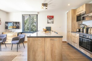 A modern kitchen with wooden cabinets, a central island, and a built-in oven. - travelski home premium - Résidence La Mariande - 3 Pièces 6 personnes N°3.3 (Les Deux Alpes)