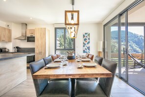 A modern kitchen with a dining area, large windows, and a view of the outdoors. - travelski home premium - Résidence La Mariande - 4 Pièces 8 personnes N°1.2 (Les Deux Alpes)