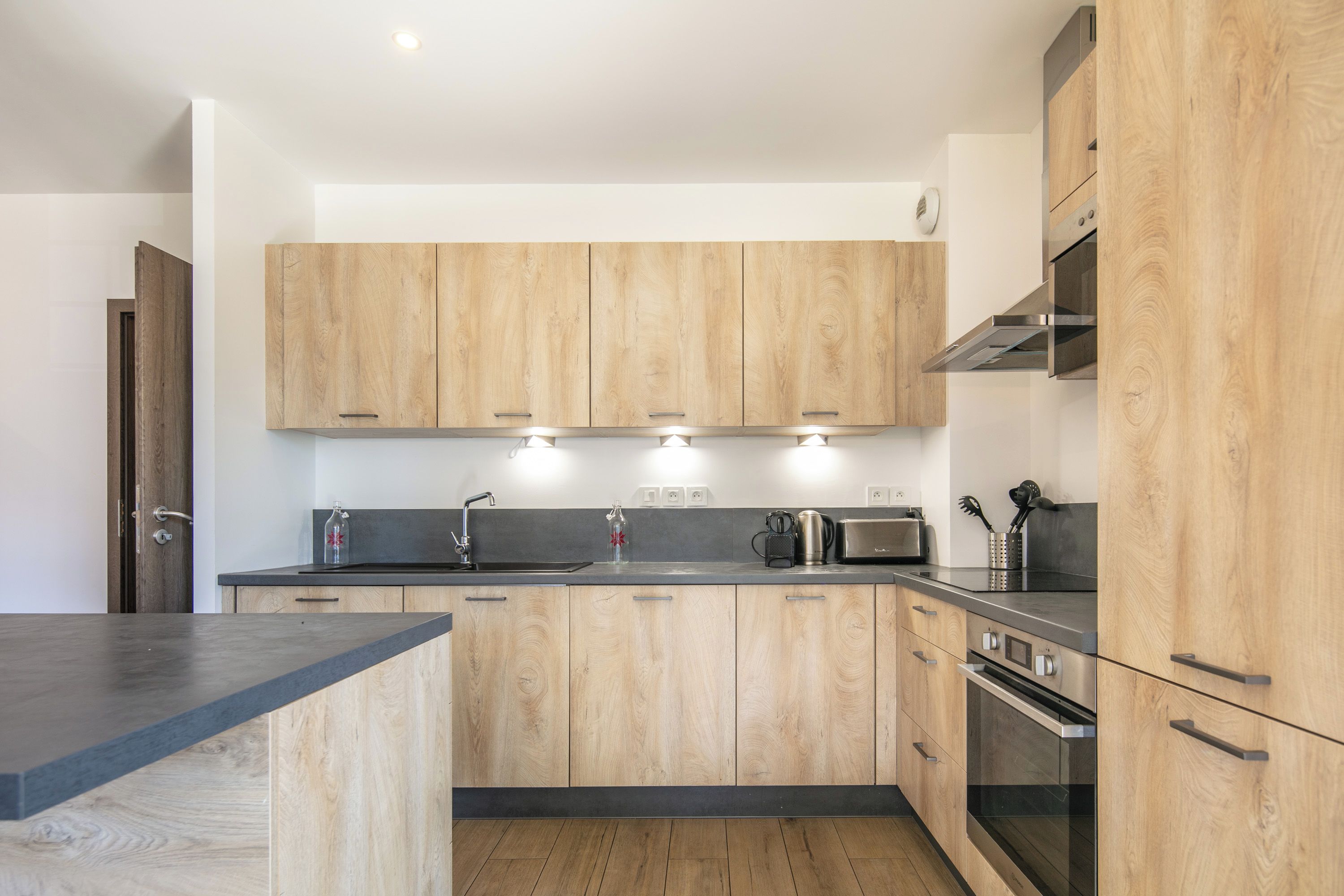 A modern kitchen with wooden cabinets, a stainless steel sink, and a built-in oven.