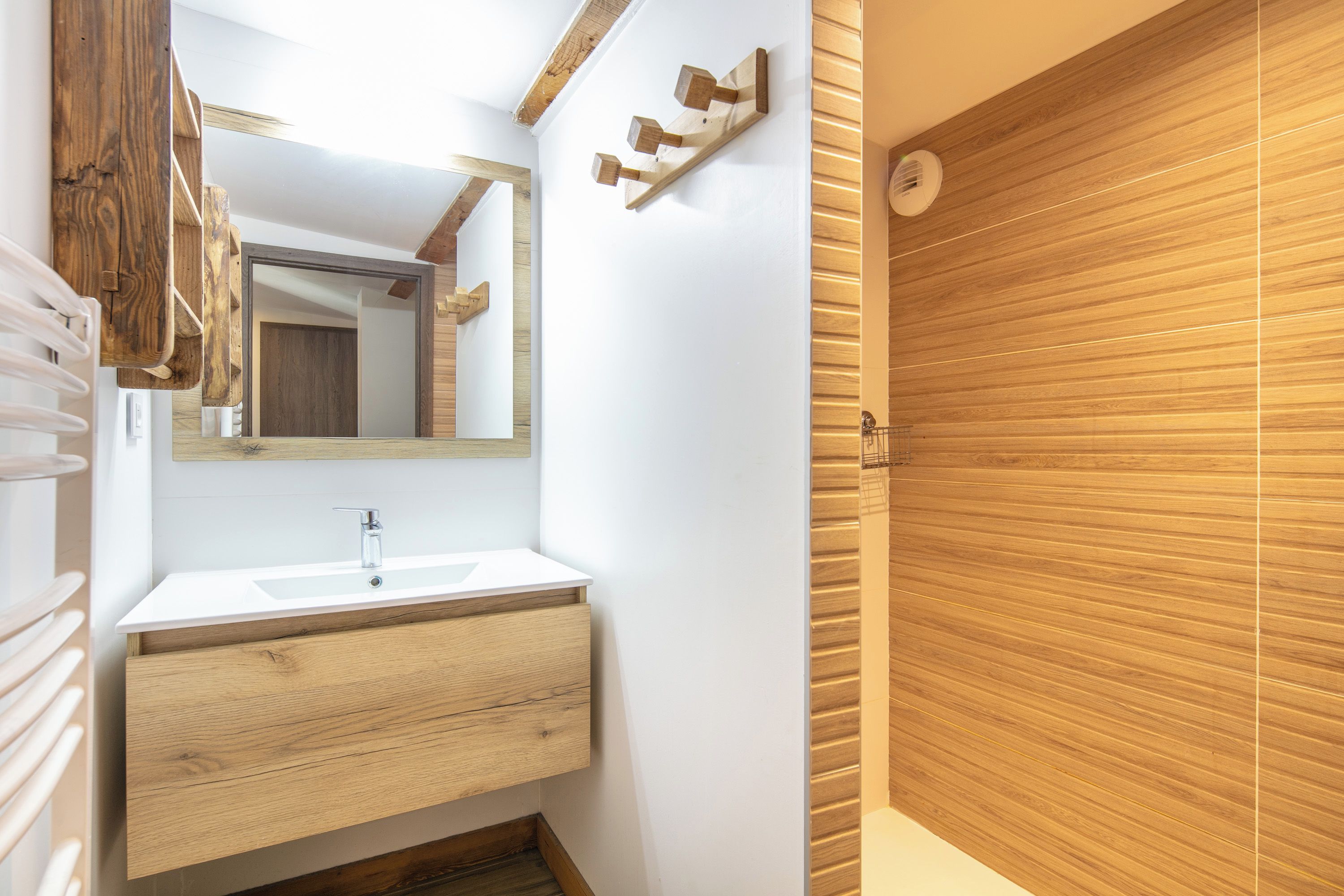Une salle de bain avec un meuble-lavabo en bois, un lavabo blanc et un miroir.