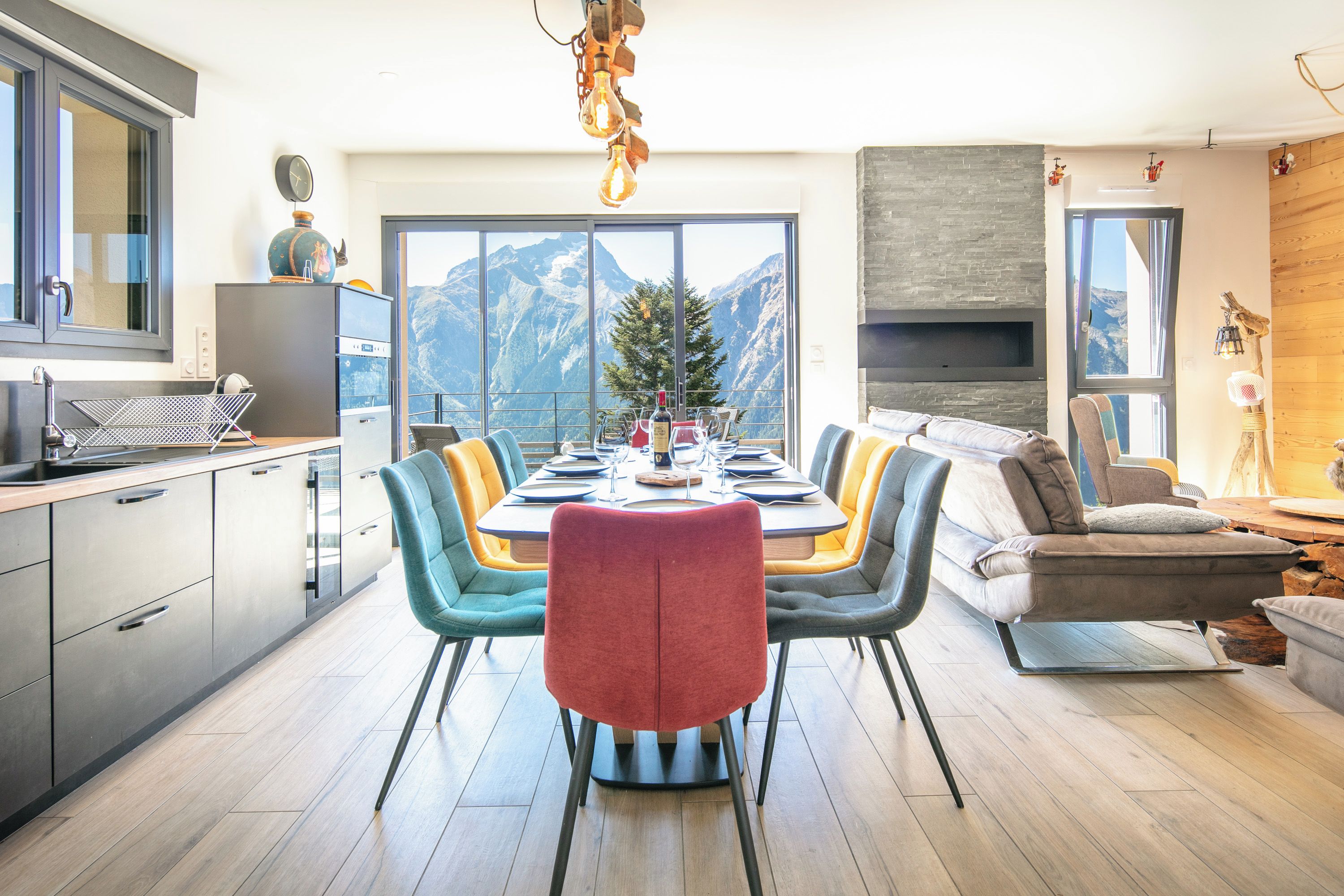 Un comedor moderno con vistas a la montaña, una cocina con electrodomésticos de acero inoxidable y un rincón de estar acogedor con chimenea.