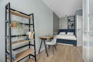 Een slaapkamer met een bed, een bureau, een stoel en een boekenplank.