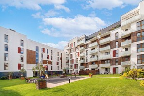 Een modern appartementencomplex met meerdere balkons en een centrale binnentuin met zitplaatsen en een speeltuin.