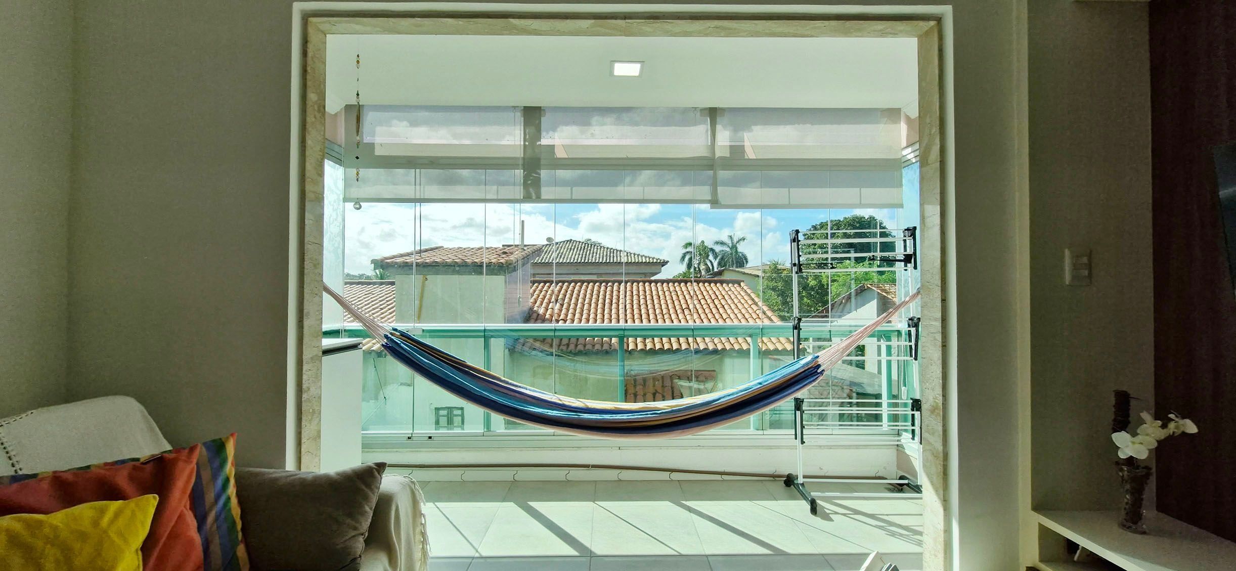 A balcony with a hammock, a view of buildings, and a tiled floor.