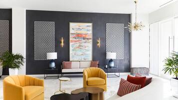 A modern living room with a sofa, armchairs, a coffee table, and a large abstract painting.