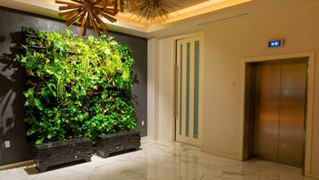 A lobby with a vertical garden, a modern elevator, and a tiled floor.