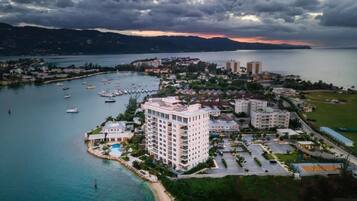 An aerial view of a coastal resort with a marina, buildings, and a beach.