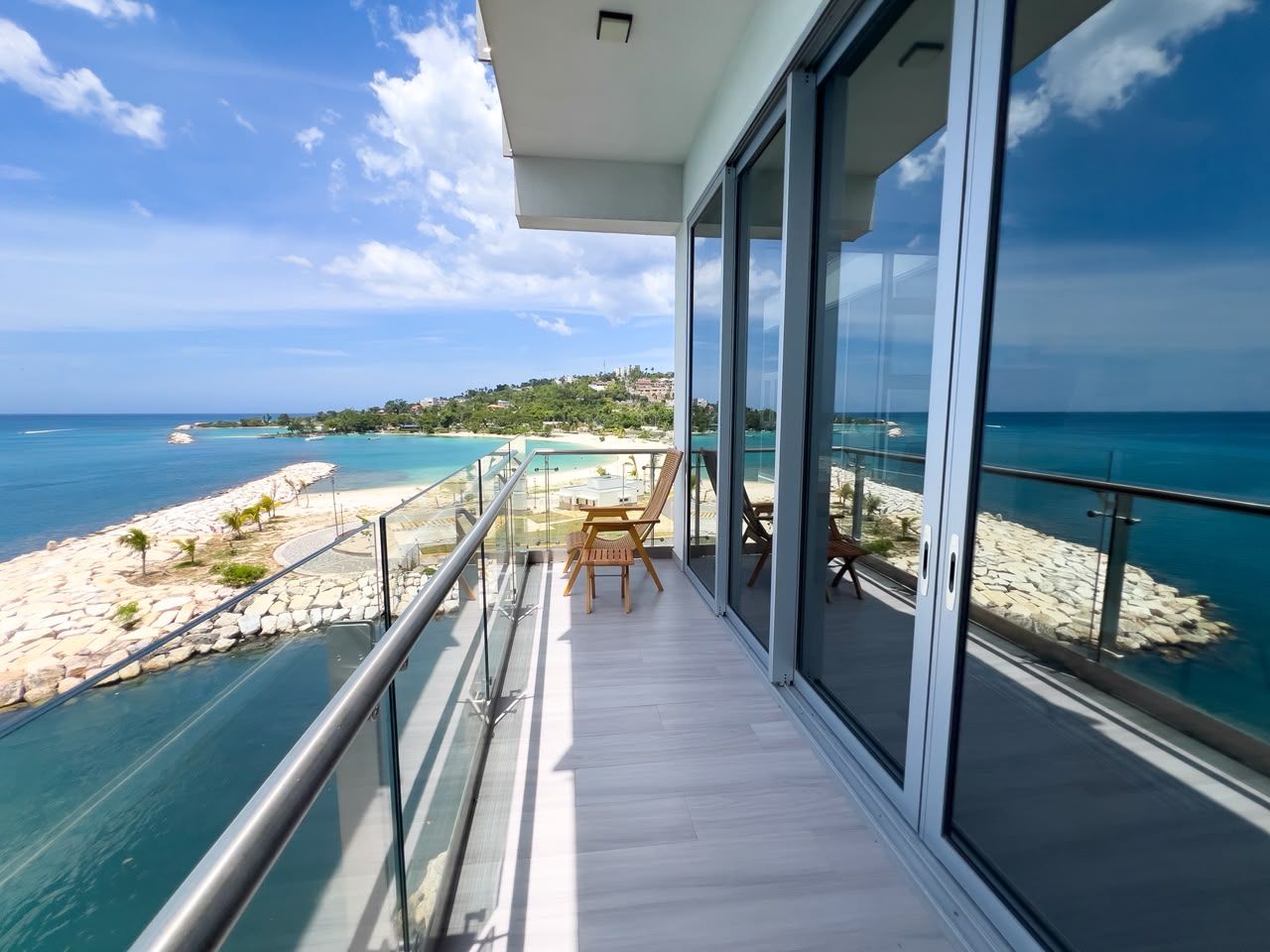 Varanda com vista para o mar, uma mesa e duas cadeiras.