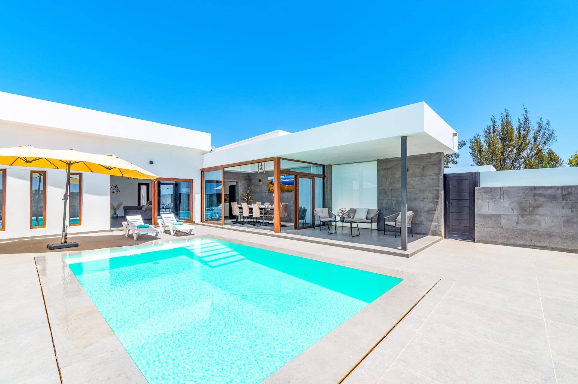 A modern house with a swimming pool, outdoor seating, and large windows.
